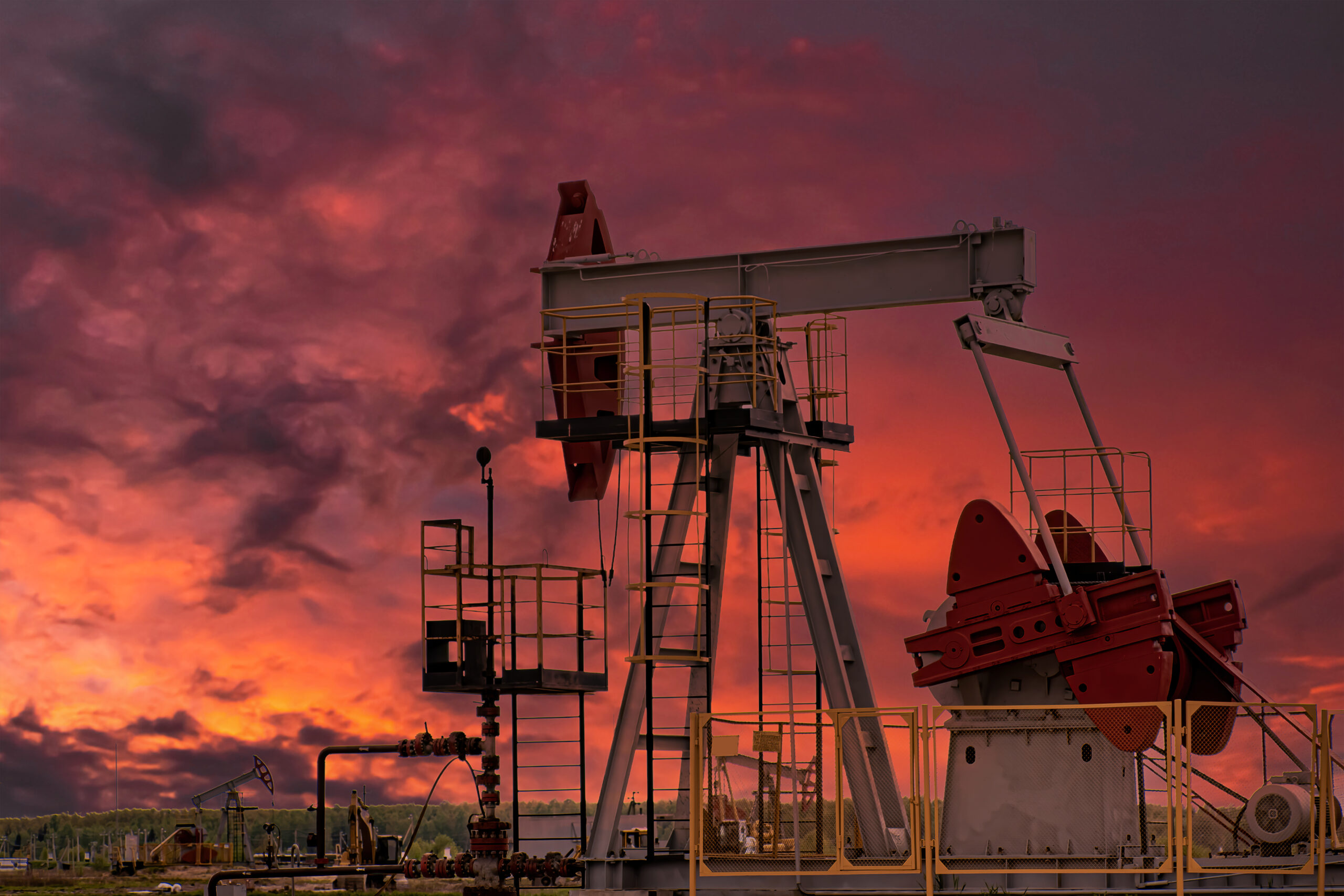 Oil drill rig and pump jack at sunset background.