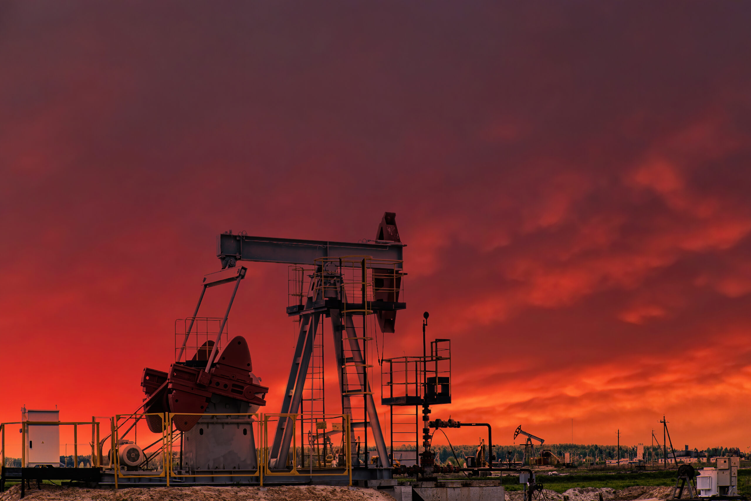 Oil drill rig and pump jack at sunset background.